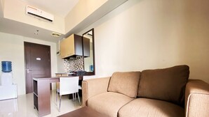 A modern living room with a sofa, a coffee table, and a dining area with a table and chairs. - Fancy And Nice 2Br Apartment At Skyland City Jatinangor (Hegarmanah)