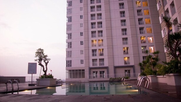 A high-rise building with a swimming pool in the foreground. - Fancy And Nice 2Br Apartment At Skyland City Jatinangor (Hegarmanah)