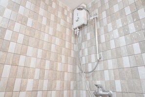 A shower area with a tiled wall and a handheld showerhead. - Minimalist And Cozy Studio At Ambassade Kuningan Apartment (Jakarta)