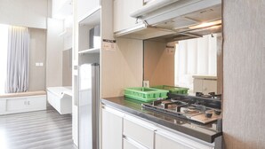 A modern kitchen with a gas stove, cabinets, and a window with curtains. - Minimalist And Cozy Studio At Ambassade Kuningan Apartment (Jakarta)