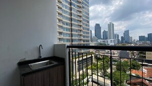 A balcony with a sink and a view of a cityscape with tall buildings. - Minimalist And Cozy Studio At Ambassade Kuningan Apartment (Jakarta)
