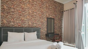 A hotel room with a stone wall, a bed with white linens, a wooden chair, and a window with curtains. - Special 1Br Direct Pool Access At Thamrin Residence (Jakarta)