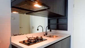 Una cucina moderna con un piano di lavoro bianco, lavello in acciaio inossidabile e piano cottura a gas.