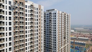 Un edificio de gran altura con varios balcones y una obra en construcción al fondo.