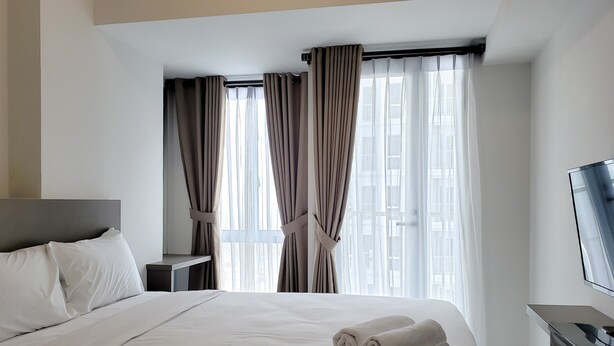 Una habitación de hotel con cama, televisión y cortinas.