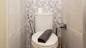 Un baño con inodoro, ducha y pared de azulejos.
