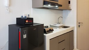 Una cocina compacta con un refrigerador negro, un lavamanos y una encimera.