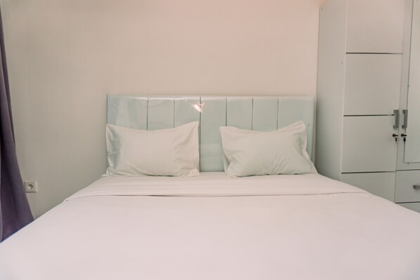 A neatly made bed with white bedding and a light blue headboard.