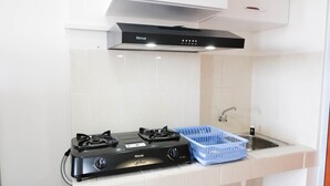 A kitchen with a Rinnai gas stove, a blue plastic basket, and a stainless steel sink. - Best Choice And Cozy Stay Studio At Puncak Kertajaya Apartment (Surabaya)