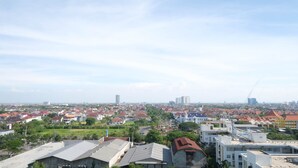 A residential area with a mix of single and multi-story houses, some with red roofs and others with grey. There are green spaces and a few taller buildings in the distance. - Best Choice And Cozy Stay Studio At Puncak Kertajaya Apartment (Surabaya)