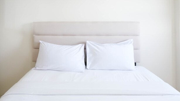 A bed with a white headboard and two white pillows. - Best Choice And Cozy Stay Studio At Puncak Kertajaya Apartment (Surabaya)