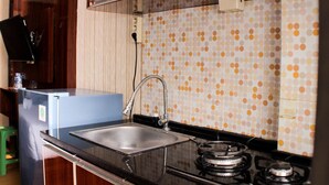 A kitchen with a stainless steel sink, a gas stove, and a refrigerator. - Cozy Studio at Lagoon Bekasi Town Square Apartment (Bekasi)