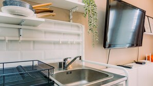 Une cuisine moderne avec un évier en acier inoxydable, des armoires blanches et une plante suspendue.