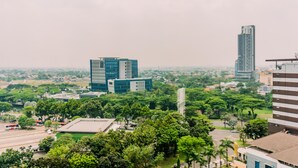 Un paysage urbain avec des bâtiments modernes, de vastes parcs verdoyants et un ciel dégagé.