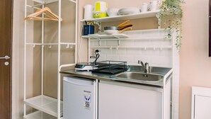 Une cuisine compacte avec des meubles blancs, un évier encastré et un petit réfrigérateur.