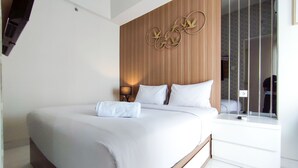 A modern hotel room with a large bed, a wooden headboard, and a wall-mounted artwork.