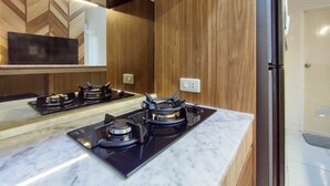 A modern kitchen with a gas stove, wooden paneling, and a marble countertop.