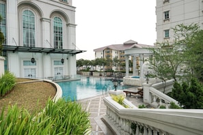 A swimming pool surrounded by buildings with large windows and a fountain. - Comfy 1Br At Bellezza Apartment (Jakarta)