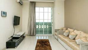 A living room with a sofa, a TV, a sliding glass door, and a ceiling fan. - Comfy 1Br At Bellezza Apartment (Jakarta)