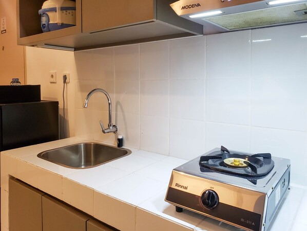 Een keuken met een roestvrijstalen spoelbak, een moderne gasfornuis en een witte betegelde spatwand.