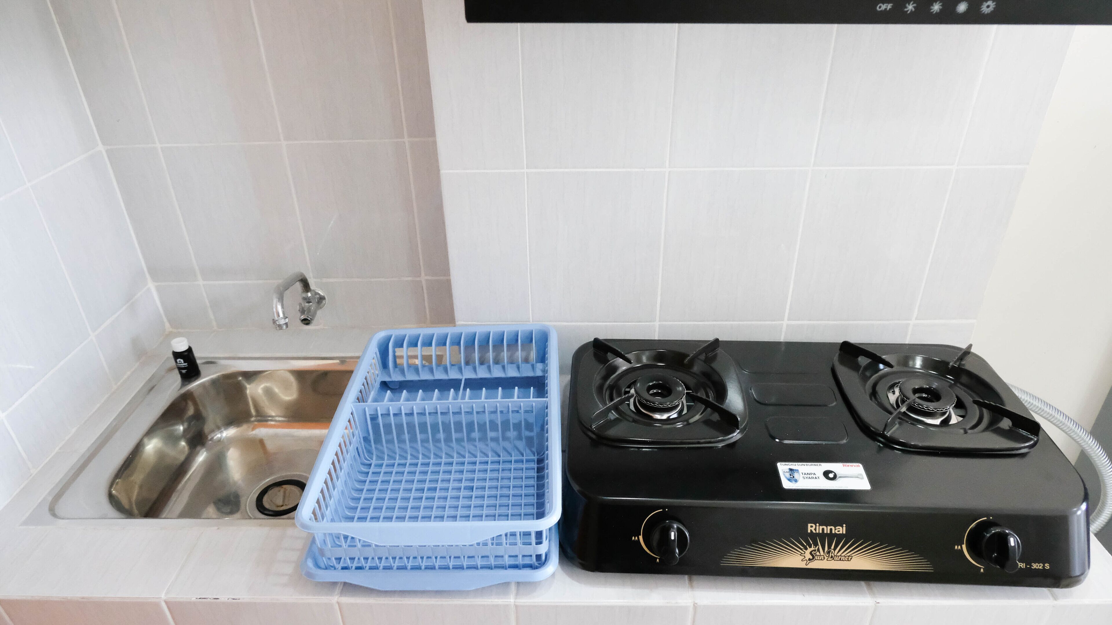 A kitchen with a double gas stove, a sink, and a blue dish rack.