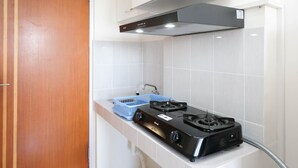 A kitchen with a gas stove, a blue dish rack, and a stainless steel range hood. - Best Deal And Comfy Studio At Puncak Kertajaya Apartment (Surabaya)
