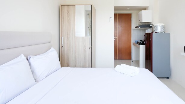A hotel room with a bed, a wardrobe, a kitchenette, and a shower area. - Best Deal And Comfy Studio At Puncak Kertajaya Apartment (Surabaya)