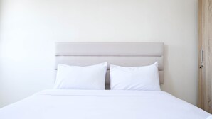 A bed with a headboard, two pillows, and a wooden door. - Best Deal And Comfy Studio At Puncak Kertajaya Apartment (Surabaya)