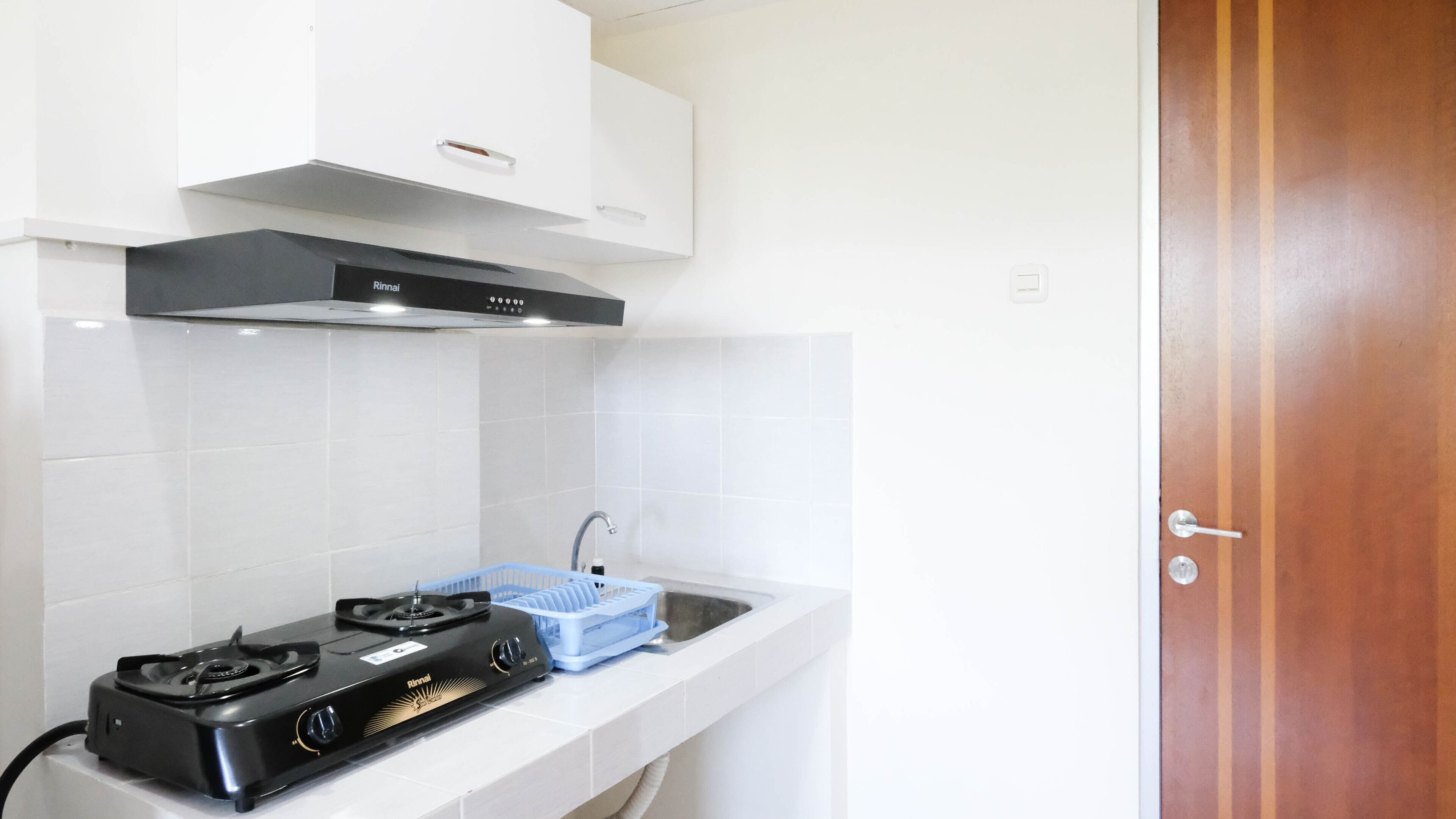 A kitchen with a gas stove, a sink, and white cabinets.