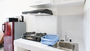 A kitchen with a gas stove, a sink, and a refrigerator. - Modern And Homey 2Br At Puncak Kertajaya Apartment (Surabaya)