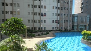 A residential building with multiple balconies, a swimming pool, and surrounding greenery. - Modern And Homey 2Br At Puncak Kertajaya Apartment (Surabaya)
