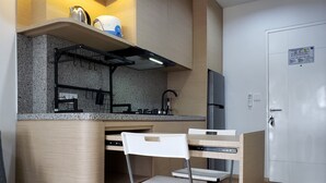 Une cuisine compacte équipée d’une cuisinière intégrée, d’un réfrigérateur et d’une chaise blanche.