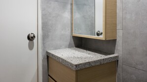 Une salle de bain avec un comptoir en granit, un meuble en bois et un miroir.