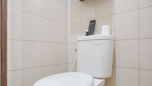 Een wit toilet met spoelknop en toiletrolhouder.
