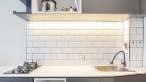 Een moderne keuken met witte metro tegels, een roestvrijstalen spoelbak en een gasfornuis.