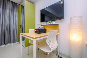 Relax in a stylish room with a flat-screen TV, a small table, and a comfortable chair.