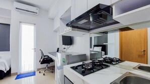 A modern kitchen with a gas stove, stainless steel sink, and a built-in oven. - Cozy Style And Comfort Studio Room Apartment At B Residence (Pagedangan)