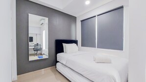 A modern bedroom with a large bed, a mirror, and a window. - Cozy Style And Comfort Studio Room Apartment At B Residence (Pagedangan)