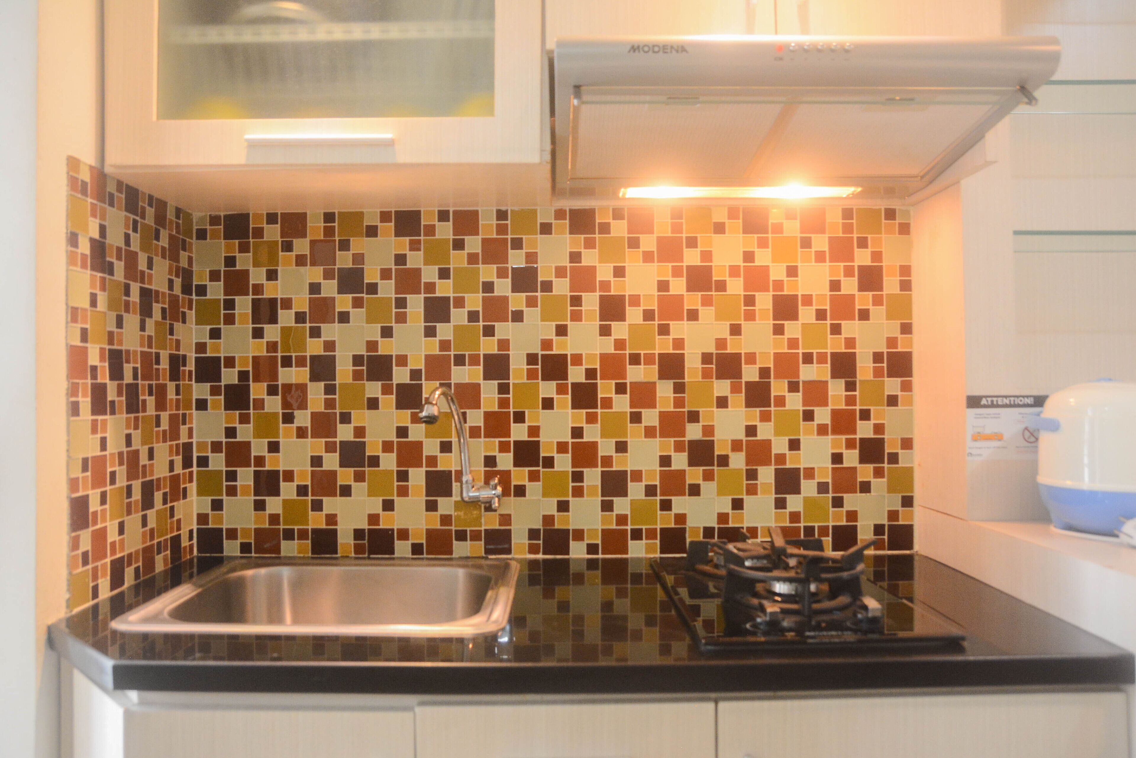 A kitchen with a tiled backsplash, a stainless steel sink, and a gas stove.