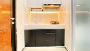 Una cocina compacta con armarios blancos, encimera negra, horno empotrado y microondas.
