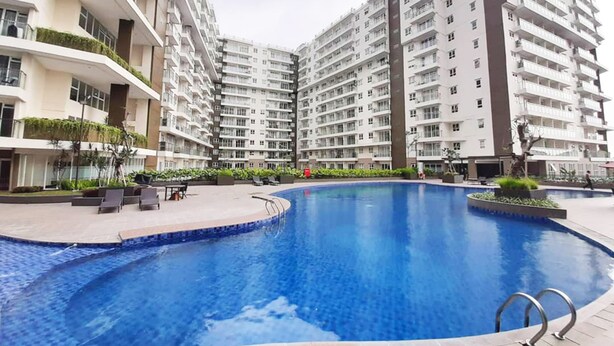 Un moderno edificio residencial con piscina central, balcones con vegetación y un área exterior bien cuidada.