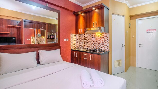 Une chambre d’hôtel avec un lit, une petite kitchenette, un miroir et une porte.