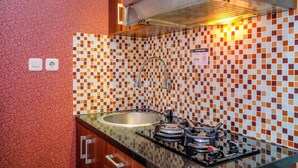 Une cuisine avec un dosseret carrelé, un évier en acier inoxydable et une cuisinière à gaz.