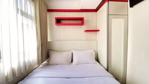 Ein Hotelzimmer mit Bett, Kleiderschrank und einem Vorhangfenster.