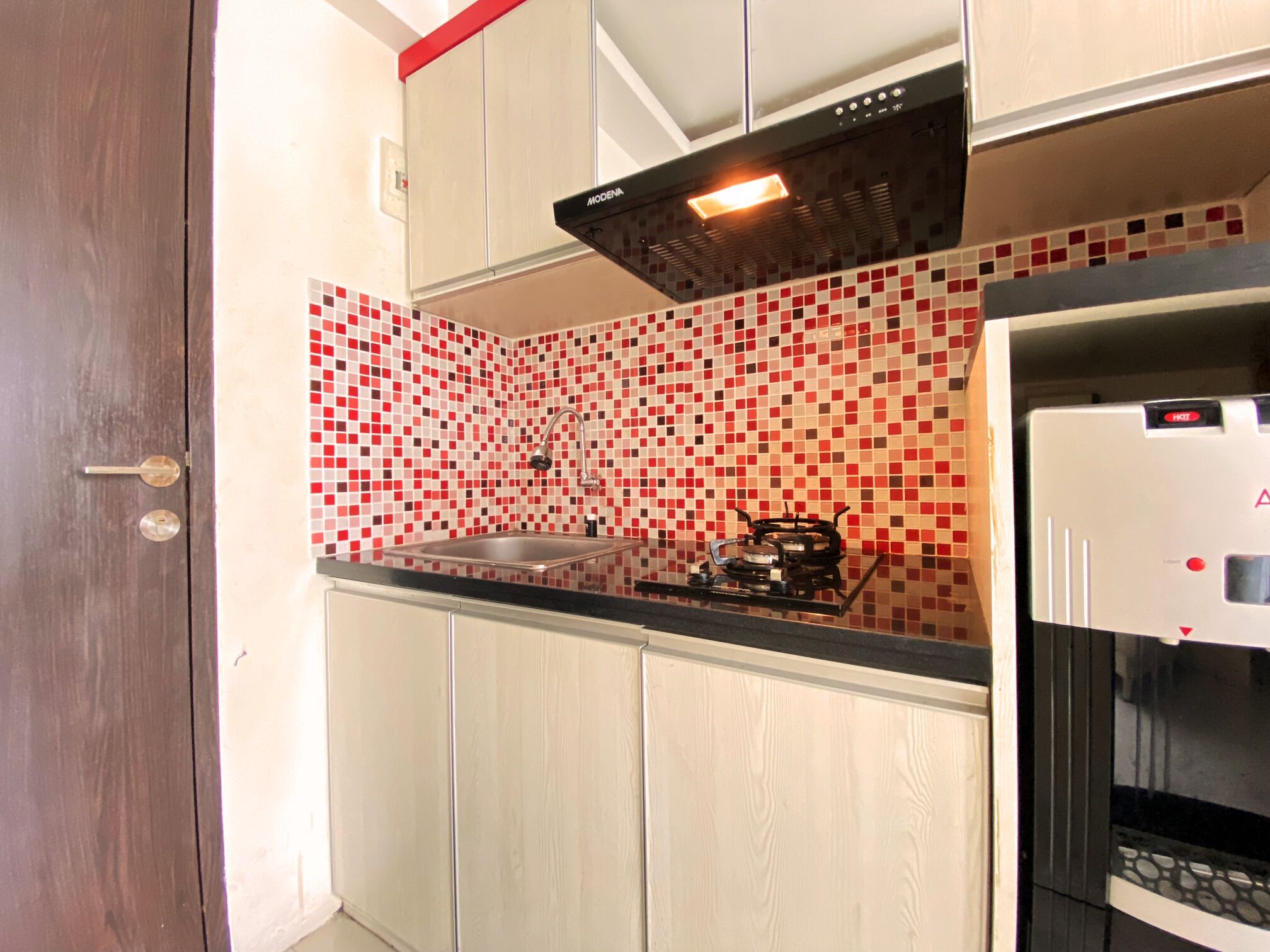 Una cocina con salpicadero de azulejos, un lavamanos de acero inoxidable, una estufa a gas y un horno empotrado.