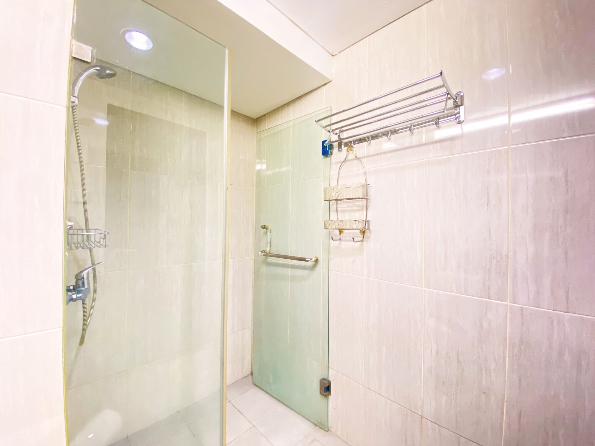 A modern bathroom with a glass shower enclosure, a towel rack, and a glass door.