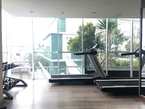 Work out with a view of the lush outdoor area from our modern gym, featuring treadmills and dumbbells.