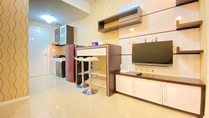 A modern kitchen with a built-in TV, a refrigerator, and a bar area. - Cozy Living 1Br Apartment At Parahyangan Residence (Bandung)