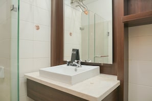 A bathroom with a white sink, a mirror, and a wooden vanity. - Cozy Studio Apartment At Woodland Park Residence (Jakarta)