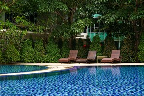 A swimming pool with lounge chairs and lush greenery. - Cozy Studio Apartment At Woodland Park Residence (Jakarta)